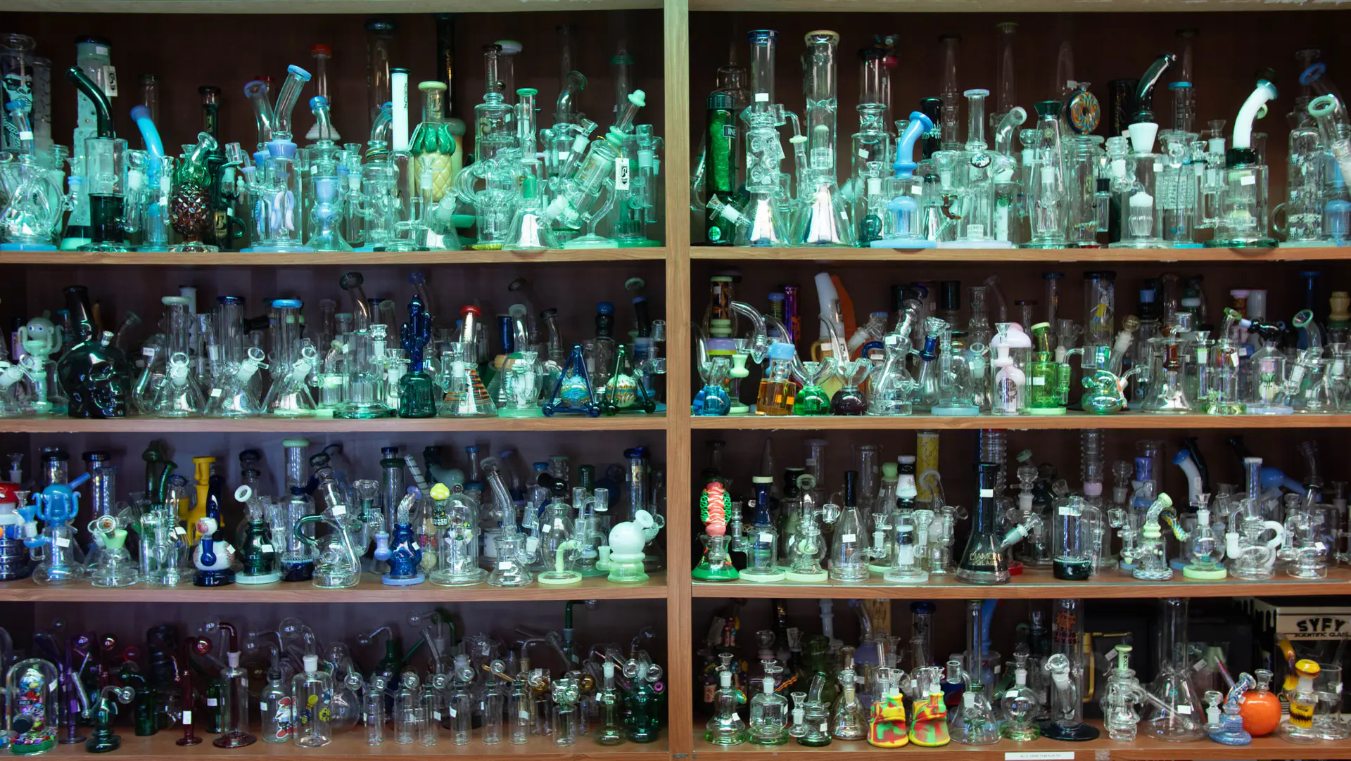 A wall of glass water pipes and rigs on wooden shelves
