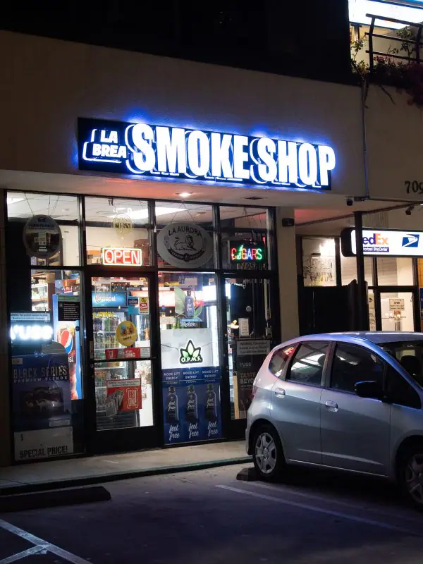 La Brea Smoke Shop storefront with its blue neon sign, in the plaza at Hollywood Blvd and La Brea Ave